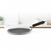 Close-up of black non-stick honeycomb roti tawa with wooden handle on white kitchen counter